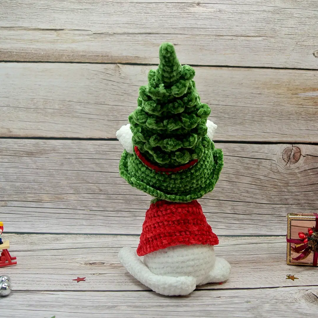 Chat blanc au crochet avec son chapeau en forme de sapin et son habit rouge vu de dos