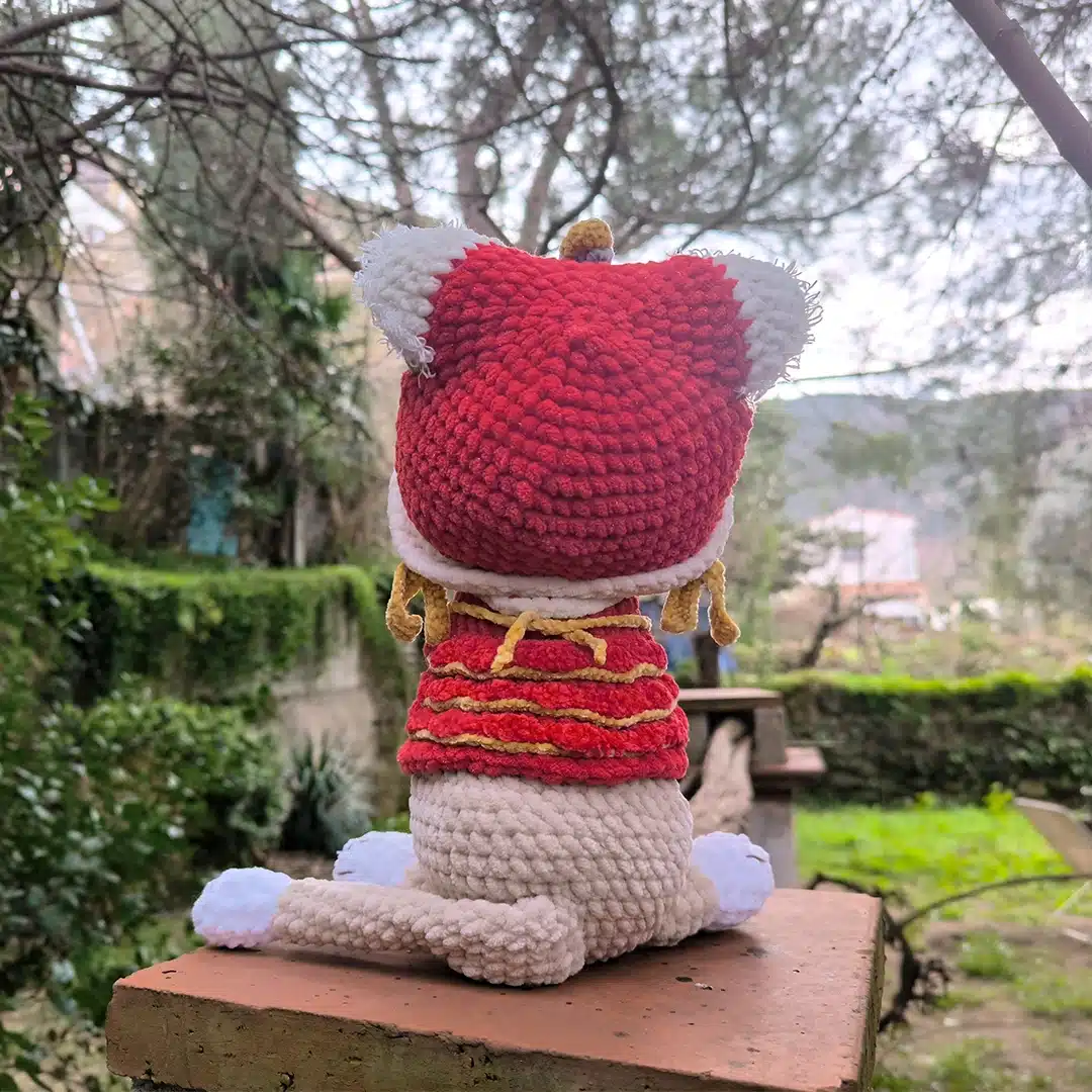 Chat au crochet et son habit rouge de dragon vu de dos