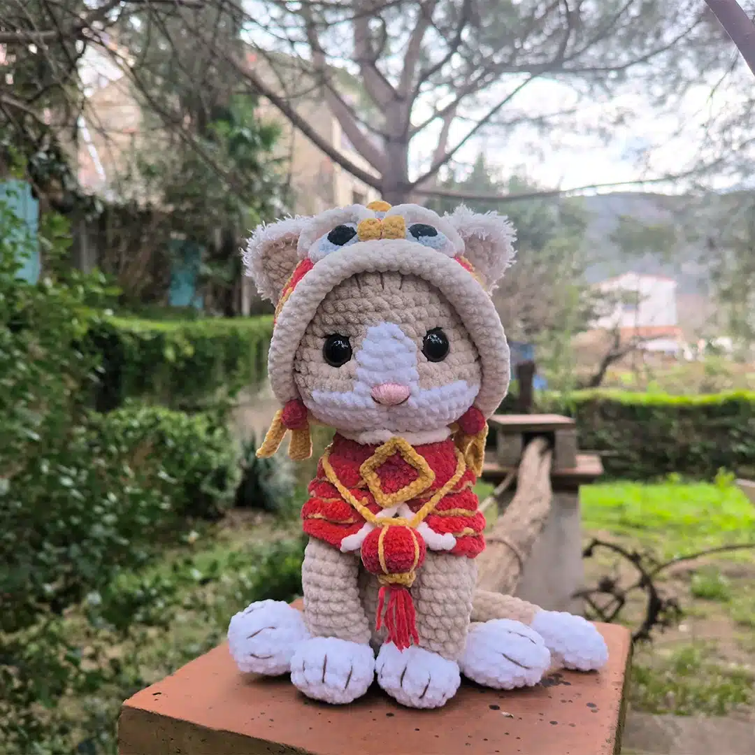 Shishimao le chat au crochet avec son habit de dragon rouge